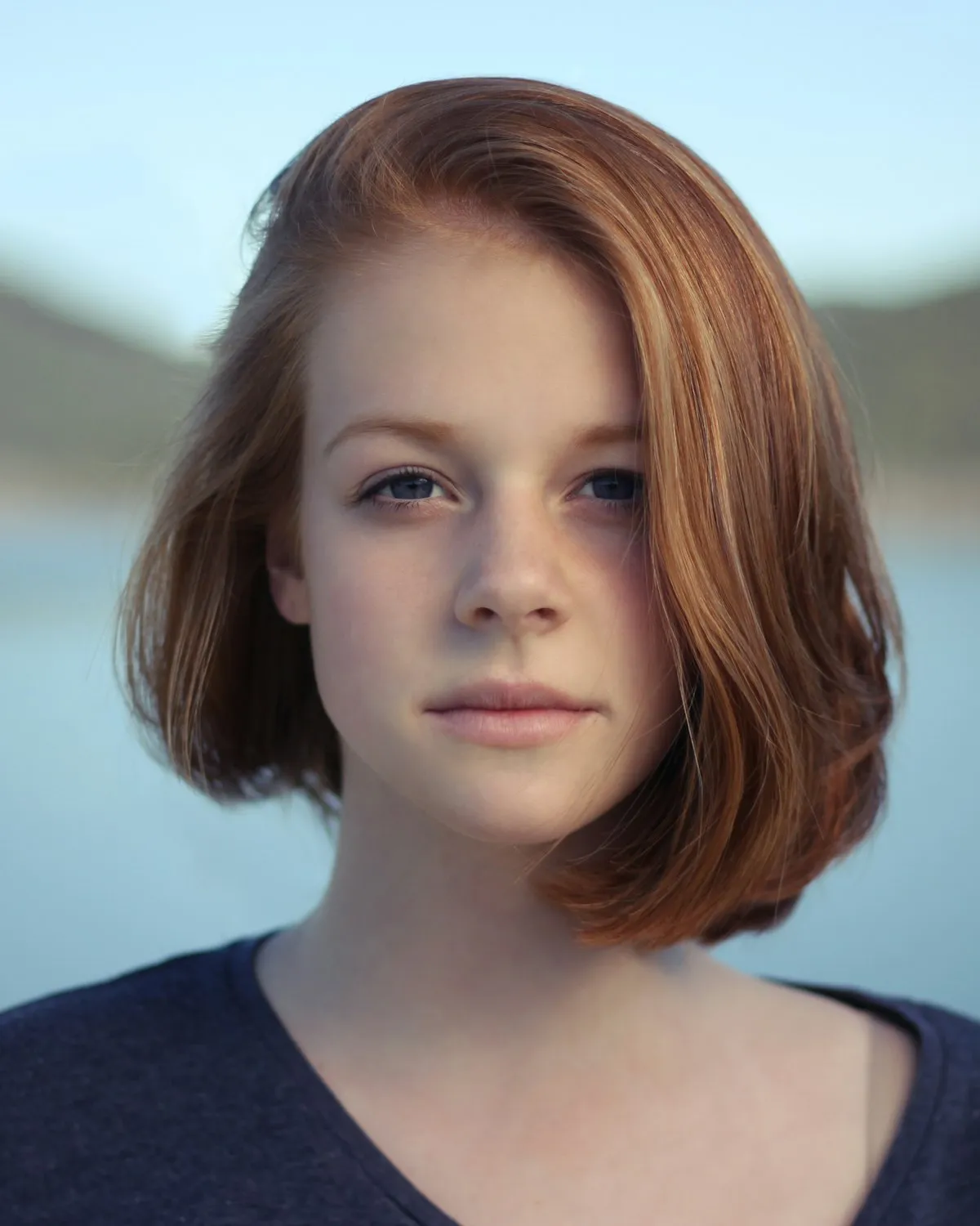 Close editorial portrait of a woman looking to camera, gentle side lighting.